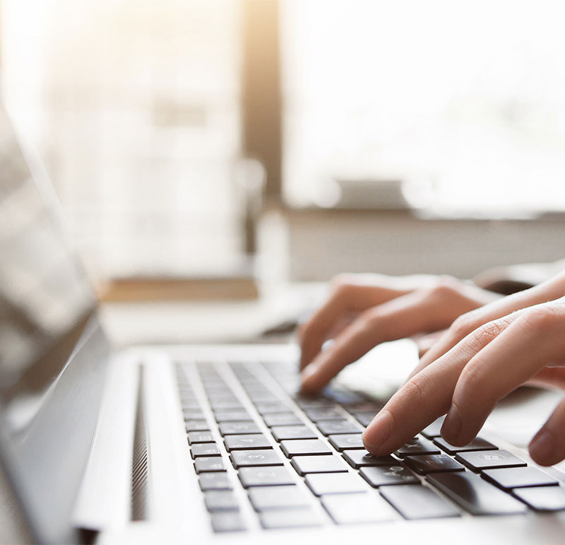 Close up of lady's hands typing on a laptop keyboard